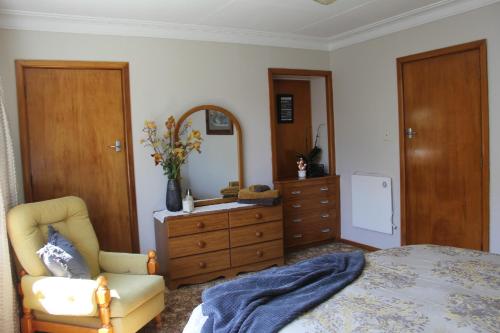 a bedroom with a bed and a dresser and a mirror at Rosies Place in Oamaru
