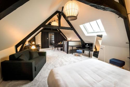 アラスにあるLe Pavillon du Golf d'Arrasのベッド、ソファ、デスクが備わる客室です。