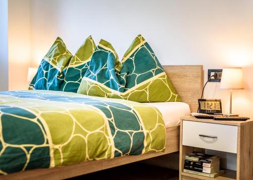 a bedroom with a bed with blue and green pillows at Apartment Studio-25 in Rijeka
