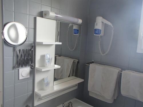 La salle de bains est pourvue d'un miroir et d'un sèche-cheveux. dans l'établissement Logis Hôtel Le pont d'Arcole, à Riscle