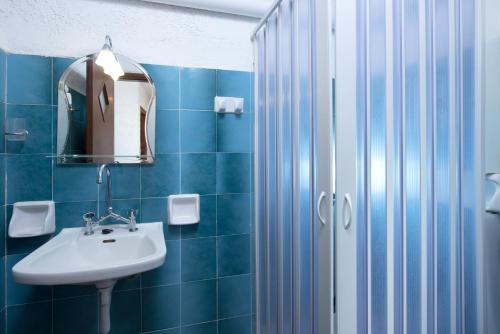 a blue tiled bathroom with a sink and a shower at Nontas Apartments in Hersonissos