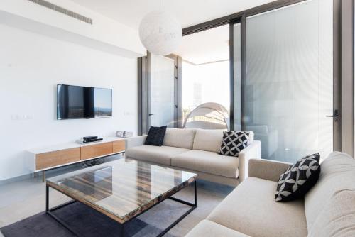 a living room with a couch and a glass coffee table at Modern 2-BR in Carmel Market by HolyGuest in Tel Aviv