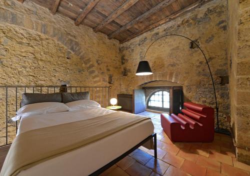 a bedroom with a bed and a red chair at Wine Relais Feudi Del Pisciotto in Niscemi