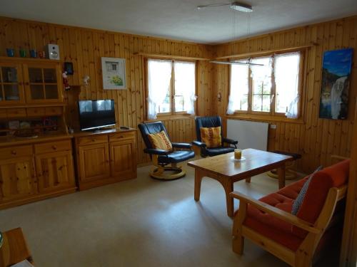 sala de estar con 2 sillas y mesa en Chalet Pinocchio, en Mühlebach