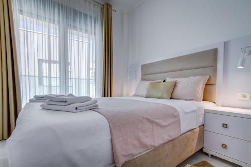 a white bedroom with a large bed and a window at Villa Blue Panorama in Budva