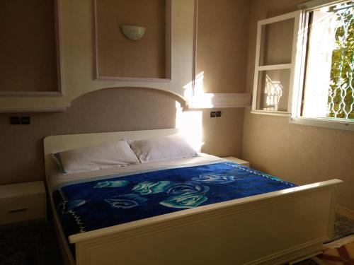 um pequeno quarto com uma cama com um cobertor azul em appartement Annakhil em Marrakech