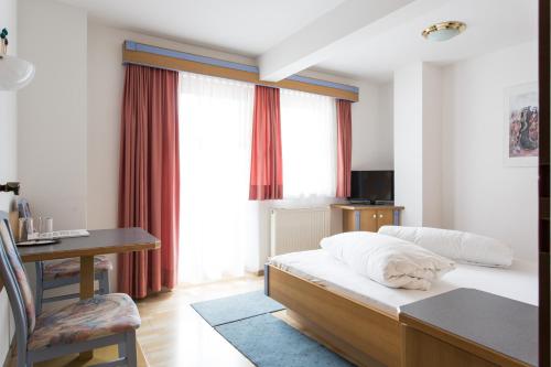 a hotel room with a bed and a desk and window at Hotel Das Zentrum in Sölden