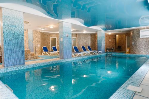 una piscina en una habitación de hotel con sillas azules en el agua en Svityaz Resort, en Truskavets