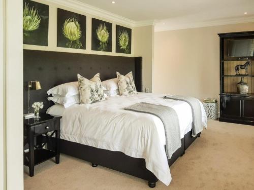 a bedroom with a large bed with a black headboard at Bosch Hoek Golf & Lodge in Balgowan