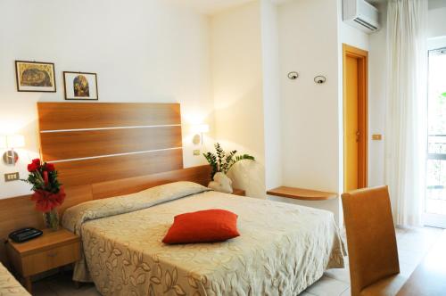 sypialnia z łóżkiem z czerwoną poduszką w obiekcie Hotel Prater w Cesenatico