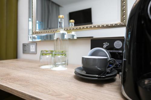 a bathroom counter with a cup and a mirror at Park Avenue J Hotel London Hyde Park in London