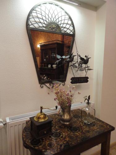 a mirror on a wall above a table with flowers at Art House Petunia in Tbilisi City