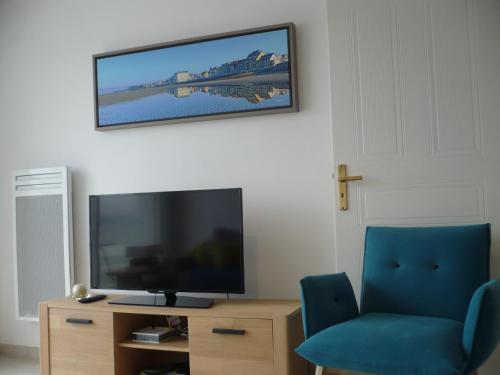 un salon avec une télévision et une chaise bleue dans l'établissement Appartement Cap Sud Vue Mer à 30m de la Plage, à Wimereux