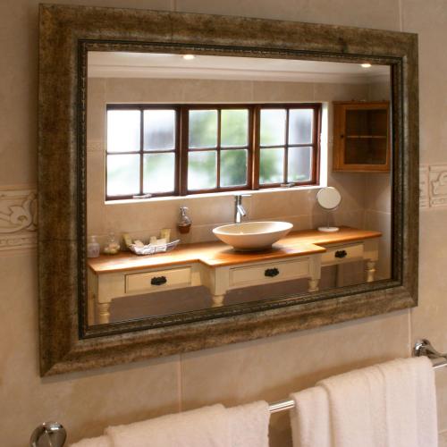 espejo en el baño con lavabo y ventana en Sacred Mountain Lodge, en Noordhoek