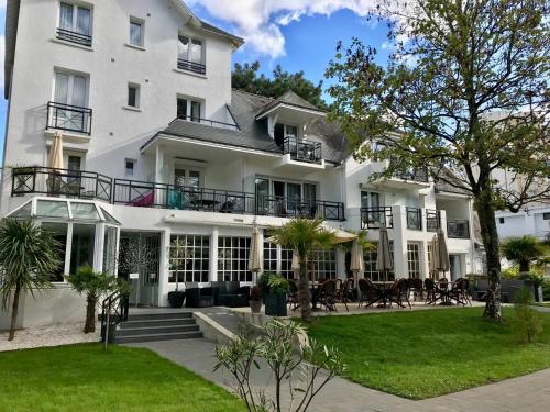 ein großes weißes Gebäude mit Leuten, die draußen sitzen in der Unterkunft Hôtel-Restaurant La Mascotte in La Baule