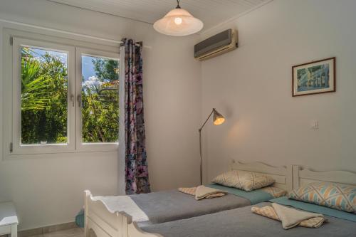 two beds in a bedroom with a window at Villa Jasmin Studios in Gouvia