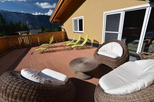 a patio with wicker chairs and tables on a deck at Villa 22 in Oetz