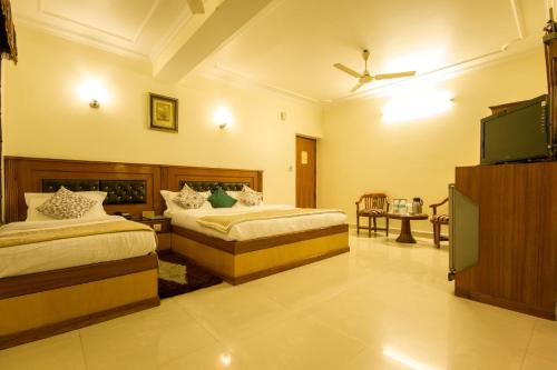 a bedroom with two beds and a flat screen tv at The C Park Inn Karol Bagh Homely Atmosphere in New Delhi