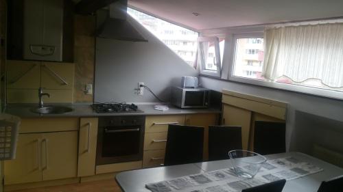 cocina con fregadero, fogones y mesa en M&F APARTAMENT JEPILOR, en Brasov