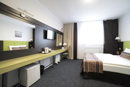クルガンにあるAvantgarde Hotel & Apartのベッドと大きな鏡が備わるホテルルームです。