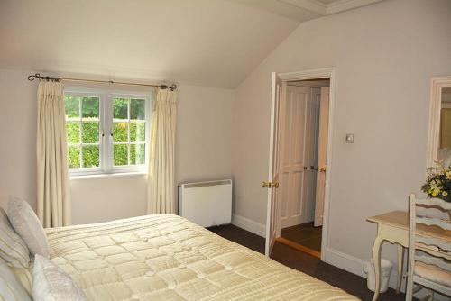 a bedroom with a bed and a table and a window at Mews Cottage in Cury