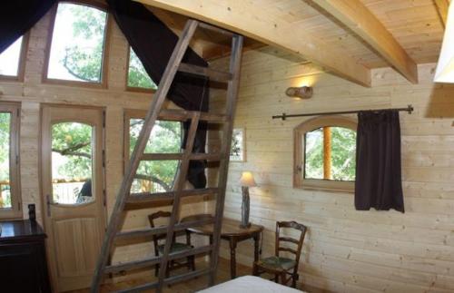 a wooden cabin with a ladder in a room at Les Cabanes en Provence in Entrechaux