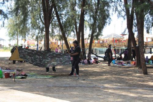 a boy is holding a hammock in a park at Marose Gold Coast Morib in Morib