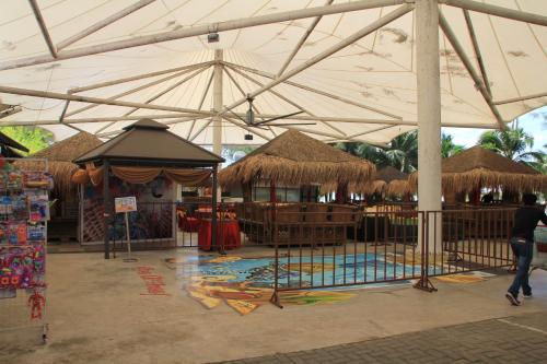 a pavilion with a pool and straw umbrellas at Marose Gold Coast Morib in Morib