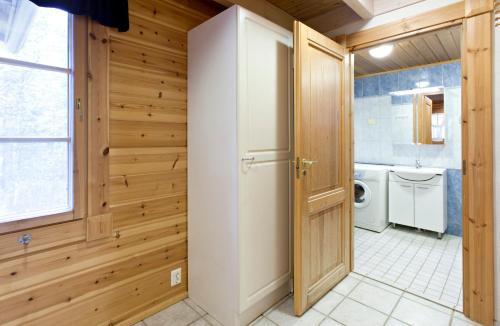 a bathroom with wooden walls and a refrigerator at Holiday Club Ähtäri Cottages in Ähtäri
