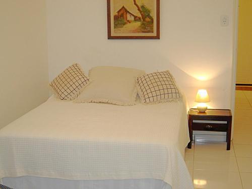 1 dormitorio con cama blanca y mesita de noche con lámpara en Studio Copacabana, en Río de Janeiro