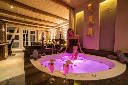 uma mulher sentada numa banheira de hidromassagem com dois copos de vinho em Spa Villa Beauty & Wellness Resort em Wingerode