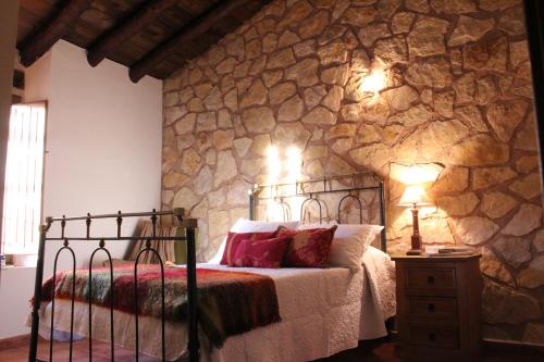 1 dormitorio con cama y pared de piedra en Casa Rural Majico, en La Pobla de Sant Miquel (Puebla de San Miguel)