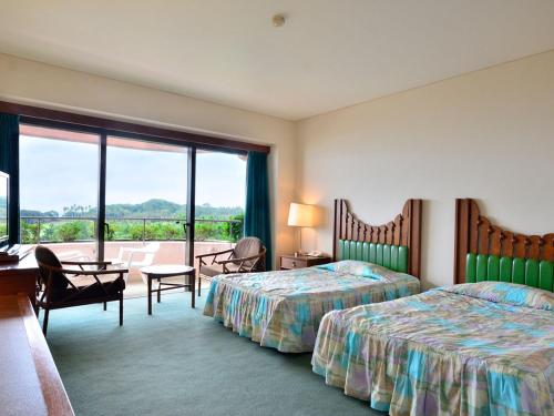 a hotel room with two beds and a balcony at Ibusuki Iwasaki Hotel in Ibusuki