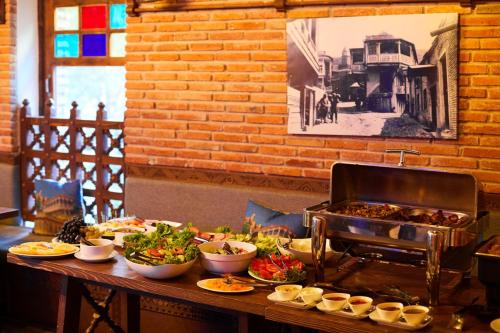 Una mesa con platos de comida y una parrilla. en Hotel Aivani Old Tbilisi, en Tiflis