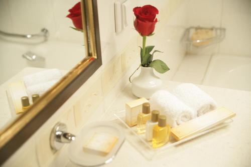 a bathroom sink with a vase with a rose in it at Grand Tien Shan Hotel in Almaty
