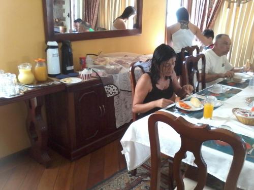 een vrouw die aan een tafel zit met een bord eten bij Village Pendotiba in Niterói