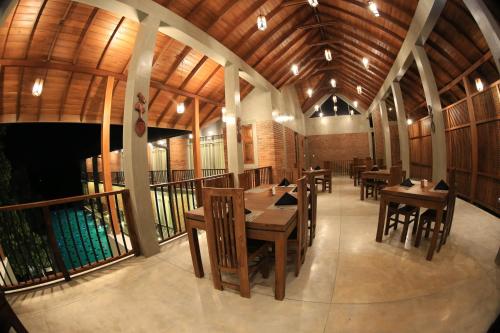 Un restaurante con mesas y sillas de madera en un edificio. en Somerset Mirissa Eco, en Mirissa