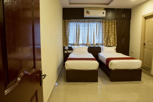 two beds in a small room with a window at Hotel Blue Bell in Bengaluru
