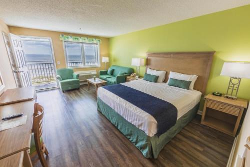 a hotel room with a bed and two chairs at The Islander Inn in Ocean Isle Beach