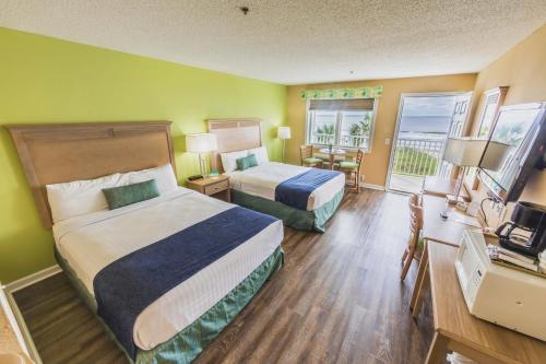 a hotel room with two beds and a balcony at The Islander Inn in Ocean Isle Beach