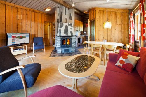a living room with a fireplace and a couch and a table at Holiday Club Pyhäniemi Cottages in Kihniö