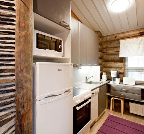 a kitchen with a white refrigerator and a sink at Holiday Club Pyhäniemi Cottages in Kihniö