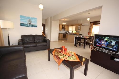 a living room with a couch and a tv at Holidays Villas in Pissouri