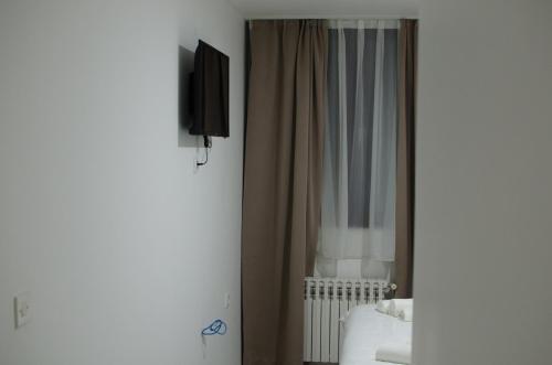 a bedroom with a bed with a television and a curtain at Hotel Metohija in Gacko