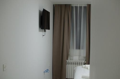 GackoにあるHotel Metohijaのベッドルーム(ベッド1台、テレビ、カーテン付)