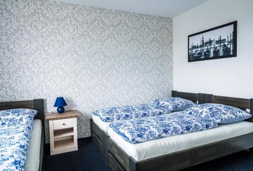 two beds in a room with blue and white sheets at Kopeček - Penzion in Česká Lípa