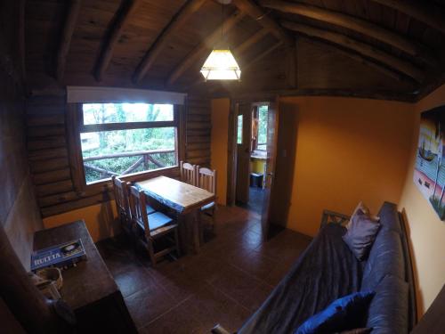 a living room with a couch and a table and a window at Cabañas Manamar in Villa Gesell