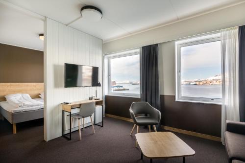 a hotel room with a bed and a desk and two windows at Smarthotel Hammerfest in Hammerfest