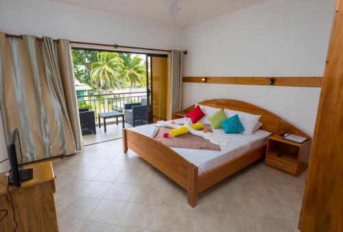 1 dormitorio con 1 cama, TV y balcón en Beach Cottages en Bel Ombre