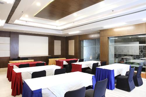 a dining room with white tables and chairs and a whiteboard at Inde Hotel Signature Tower in Gurgaon